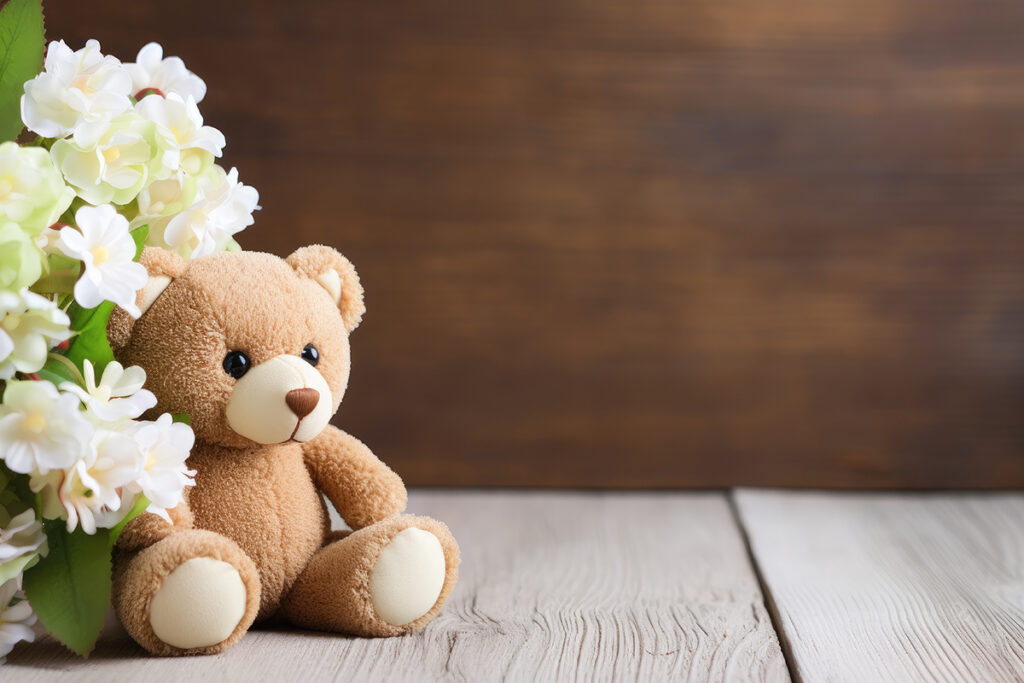 Teddy bear and white flower on wooden background accompany sympathetic card