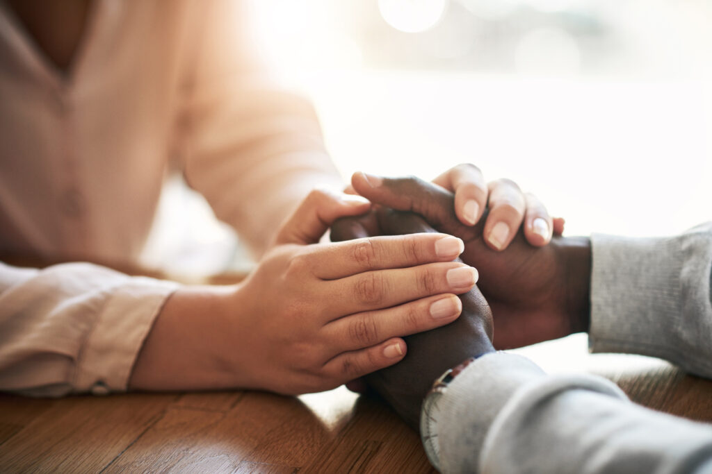 Closeup of hands of couple holding in loving support of care and comfort after grieving loss. Kind friends express sympathy and trust for each other in sweet and caring gesture together.