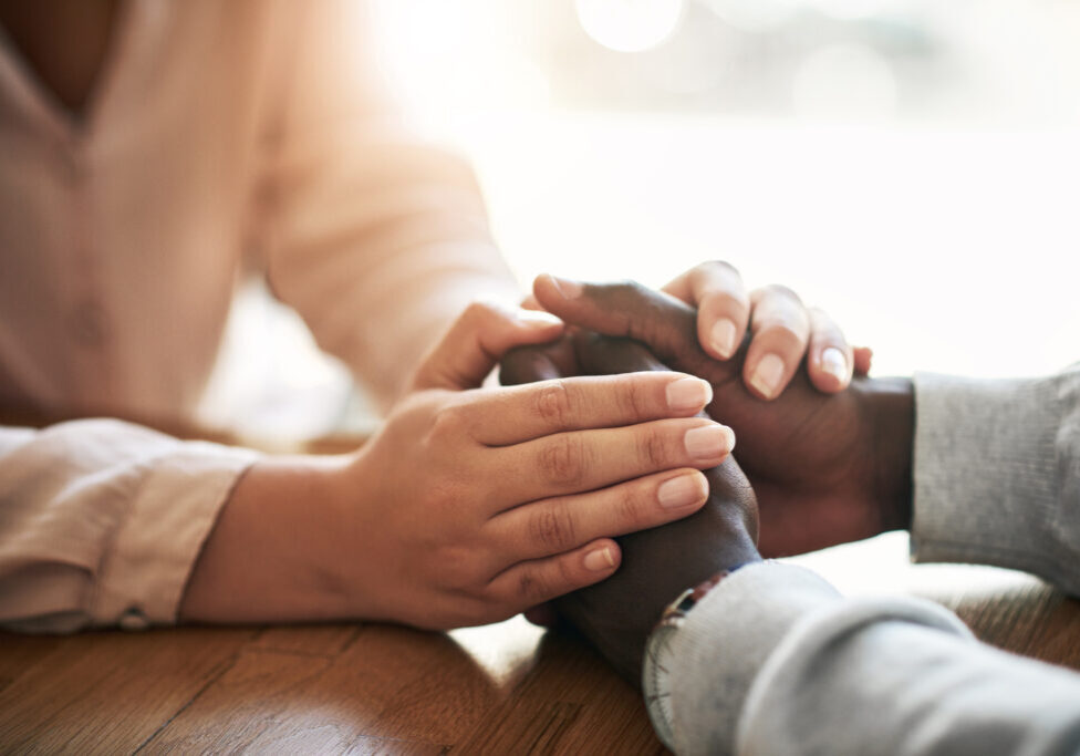 Closeup of hands of couple holding in loving support of care and comfort after grieving loss. Kind friends express sympathy and trust for each other in sweet and caring gesture together.